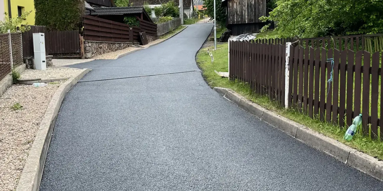 Nový asfaltový povrch místní komunikace v Bělé u Pecky po uložení kabelů